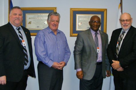 Barnstable County Sheriff Jim Cummings, second from left, poses with audit team from American Correctional Association following closeout meeting on Friday.  The 100%-compliance audit means a new certificate like the ones on the wall here, continuing the Bourne correctional facility’s accreditation through 2019.  Auditors, starting from left, include Brian Bivens, Ernest Umunna, and Delbert Longley.
