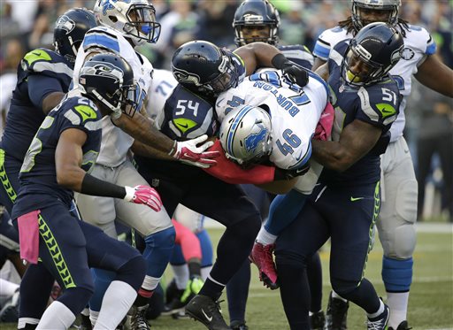 Detroit Lions fullback Michael Burton (46) is tackled by Seattle Seahawks outside linebacker Bruce Irvin, right, and middle linebacker Bobby Wagner (54) in the first half of an NFL football game, Monday, Oct. 5, 2015, in Seattle. (AP Photo/Elaine Thompson)