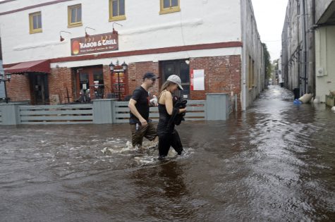 Residents Julia Schittko and Nathan Ogdon walk along flooded Water Street in Wilmington, N.C., Saturday, Oct. 8, 2016 as Hurricane Matthew moves into the Carolinas. Matthew continued its march along the Atlantic coast Saturday, lashing two of the South's most historic cities and some of its most popular resort islands, flattening trees, swamping streets and knocking out power to hundreds of thousands. (AP Photo/Gerry Broome)