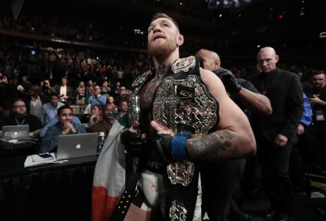 Conor McGregor leaves the octagon with his title belts after knocking out Eddie Alvarez during a lightweight mixed martial arts bout at UFC 205, early Sunday, Nov. 13, 2016, at Madison Square Garden in New York. (AP Photo/Julio Cortez)