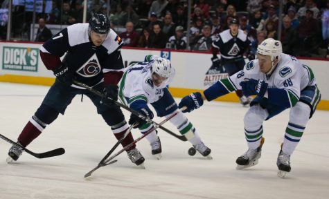 Vancouver Canucks defenseman Nikita Tryamkin (88) and left wing Loui Eriksson (21) defend Colorado Avalanche center John Mitchell during overtime of an NHL hockey game, Saturday, Nov. 26, 2016 in Denver. Vancouver won 3-2 in a shootout. (AP Photo/Joe Mahoney)