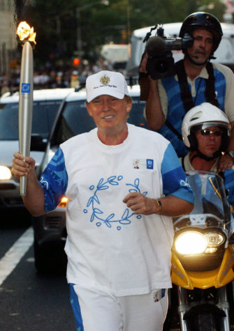 FILE - In this Saturday, June 19, 2004 file photo, Donald Trump carries the Olympic Flame on New York's Fifth Avenue during day 15 of the 2004 Athens Torch Relay. The Olympic torch snaked through the streets of New York while raising hopes of a possible 2012 Olympics for the Big Apple. President-elect Donald Trump has been a longtime admirer of the Olympics. He also likes winning. That should make him a natural supporter of the effort to bring the Olympics back to Los Angeles in 2024. (AP Photo/Chad Rachman, Pool, File)