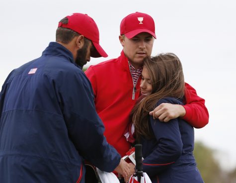 FILE - In this Oct. 11, 2015, file photo, United States' Jordan Spieth, center, is embraced by his girlfriend Annie Verret following his loss to International team player Marc Leishman of Australia in their singles match as Dustin Johnson, left, watches at the Presidents Cup golf tournament at the Jack Nicklaus Golf Club Korea, in Incheon, South Korea. Spieth is out of the Olympics. International Golf Federation president Peter Dawson announced the decision at the British Open. Spieth had been strongly debating whether to go over the last three days before reaching his decision on Monday, July 11, 2016. He will be replaced by Matt Kuchar. (AP Photo/Lee Jin-man, File)