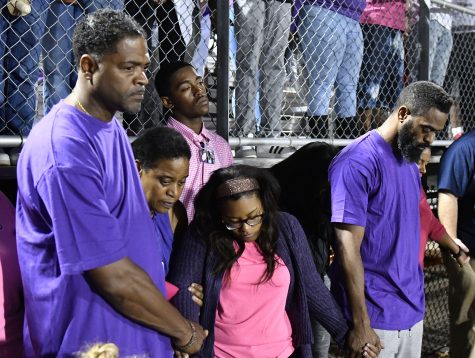 Tyson Gay, right, and Shoshana Boyd, second right, mother of Trinity Gay, hold hands during a moment of silence at a memorial service for their slain daughter at Lafayette High School, Monday, Oct. 17, 2016, in Lexington, Ky. Several thousand people, turned out Monday night for a candlelight vigil in Kentucky to honor their 15-year-old daughter, who was fatally shot over the weekend. (AP Photo/Timothy D. Easley)