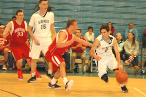 Sandwich High School senior captain Joey Downes makes a move to the basket on Barnstable's Nate Balthazard as the Blue Knights' Henry O'Brien and Barnstable's Will O'Day watch him blaze by. Sean Walsh/CCBM Sports