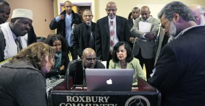FILE - In this March 31, 2015 file photo, Muslim, Christian, minority and government leaders fix their eyes on a laptop screen showing a video as part of a federal pilot program called Countering Violent Extremism, at Roxbury Community College in Boston. Seated at center right is Carmen Ortiz, U.S. Attorney for Massachusetts. More than a year and a half after it was first announced, the federal effort in Boston, Los Angeles, and Minneapolis to combat extremist recruitment has been slow to start. Few local programs have been directly created by the Countering Violent Extremism" pilot initiative, with officials in those cities just starting to distribute more than $500,000 in Department of Justice grant money to jumpstart new local efforts. (AP Photo/Charles Krupa, File)