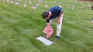 Monument Beach resident Scott Silva plants a flag on a veteran's gravesite. 