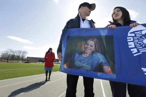 ADVANCE FOR MONDAY, APRIL 21, 2014 - In this Thursday, April 17, 2014, photo, University of Massachusetts nursing students Spencer Gilfeather, center, and Sarah Gasse, right, hold a banner that features a photo of Krystle Campbell, a UMass nursing student who died in the marathon bombings, during a tribute walk on a track at the school in Boston. Gasse obtained her bib number to run this years race through a special application process added to include those personally and profoundly affected by last years attacks. (AP Photo/Steven Senne)