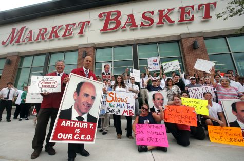 FILE - In this July 24, 2014 file photo, Market Basket assistant managers Mike Forsyth, left, and John Surprenant, second from left, hold signs while posing with employees in Haverhill, Mass. A documentary We the People: The Market Basket Effect will be shown in select Boston area theaters April 14, 2016. The distributor, FilmBuff, says it will also be released on-demand. The film chronicles the feud within the family that owns and operates the Market Basket grocery chain and an ensuing 2014 walkout by employees loyal to ousted CEO Arthur T. Demoulas. (AP Photo)