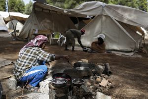 A Syrian man cooks on a makesift fire at Ritsona refugee camp north of Athens, which hosts about 600 refugees and migrants on Monday, Sept. 19, 2016. The European Union's border agency says the number of migrants arriving in the Greek islands has increased significantly over the last month. (AP Photo/Petros Giannakouris)