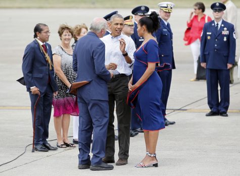 Rep. Bill Keating, D-Mass, left, gives President Barack Obama a golf ball as he greets the him and the first lady Michelle Obama, right, at the Cape Cod Coast Guard Station in Bourne, Mass., Saturday, Aug. 6, 2016, en route to Martha's Vineyard. (AP Photo/Stew Milne)