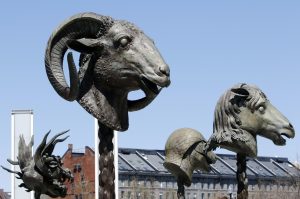In this Wednesday, April 27, 2016 photo, four of 12 gigantic bronze animal heads representing the signs of the Zodiac by Chinese artist Ai Weiwei stand in a circle on the Rose Kennedy Greenway in Boston. Lucas Cowan, the public art curator of the Greenway Conservancy, says they are replicas of smaller sculptures stolen from an imperial Chinese palace in 1860. The sculptures are scheduled to remain on public display in the park through October. (AP Photo/Bill Sikes)