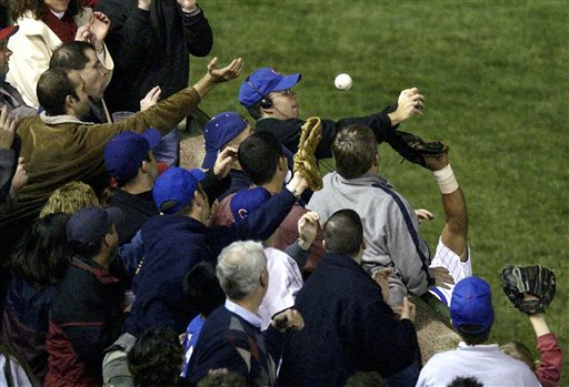 FILE - In this Oct. 14, 2003 file photo, Chicago Cubs left fielder Moises Alou's arm is seen reaching into the stands, at right, unsuccessfully for a foul ball along with fan Steve Bartman, left, wearing headphones, glasses and a Cubs hat, during the eighth inning against the Florida Marlins in Game 6 of the National League Championship Series in Chicago. Twelve years after that fateful night when he deflected a foul ball that appeared destined to land in Alou's glove and help land the Cubs in the World Series for the first time since 1945, it is tough to find someone who has a bad thing to say about Bartman. (AP Photo/Morry Gash, File)