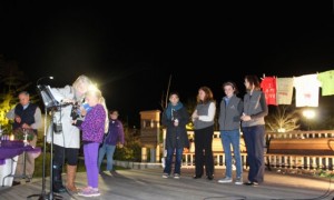 CCB MEDIA PHOTO Diane Pratt, executive director of the Cape Cod Center for Women, helps a young girl at the microphone at the second annual Candlelight Vigil to raise awareness about domestic violence at Peg Noonan Park in Falmouth.