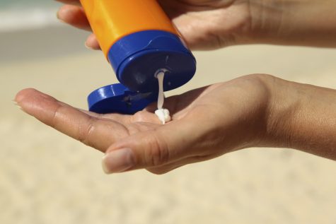 woman holding and applying suntan lotion on a beach