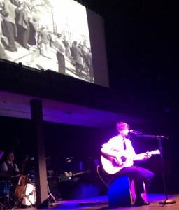 James Davis sings Donovan's "The War Drags On" as images of Vietnam are projected behind him in "The Beat Goes On" at Cotuit Center for the Arts.