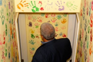 CCB MEDIA PHOTO Children's Cove Associate Director Lenny Fontes walks through the stairway lined with handprints to the interview room. The handprints are meant to help children realize they are not alone in suffering abuse.