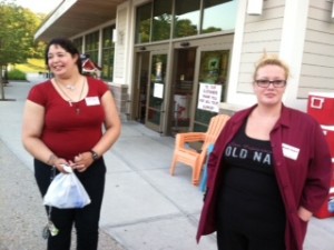 Market Basket staffers Kim-Ray Gomes, 28, who is head of cakes and desserts in the bakery, and Allyssa Cooke, 27, who is a cashier, talk to customers outside the store during their off-hours.