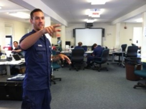 Coast Guard Public Affairs Specialist Ross Ruddell points out the different sections of the command center set up in the Barnstable County Health and Human Services building.